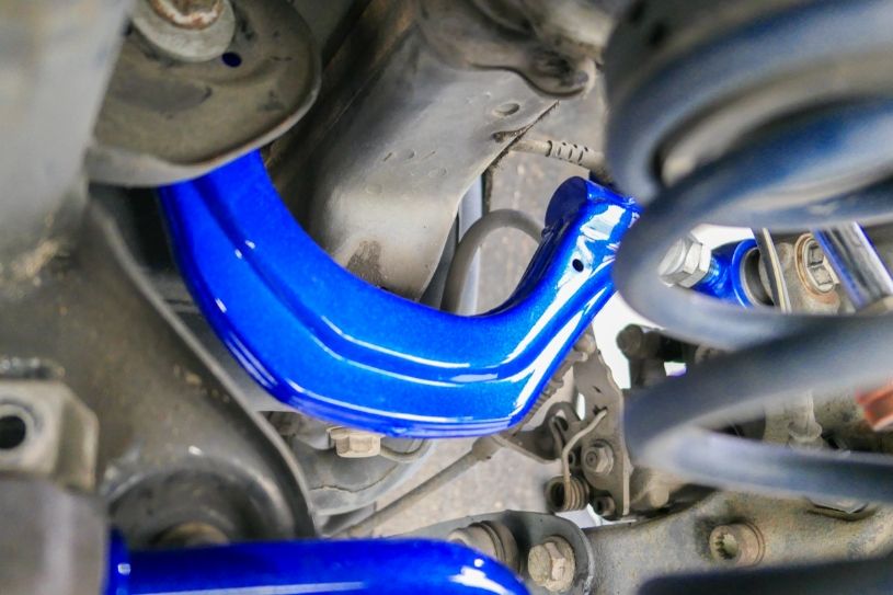 Close-up of a blue suspension component on a vehicle, with springs and metal parts visible.